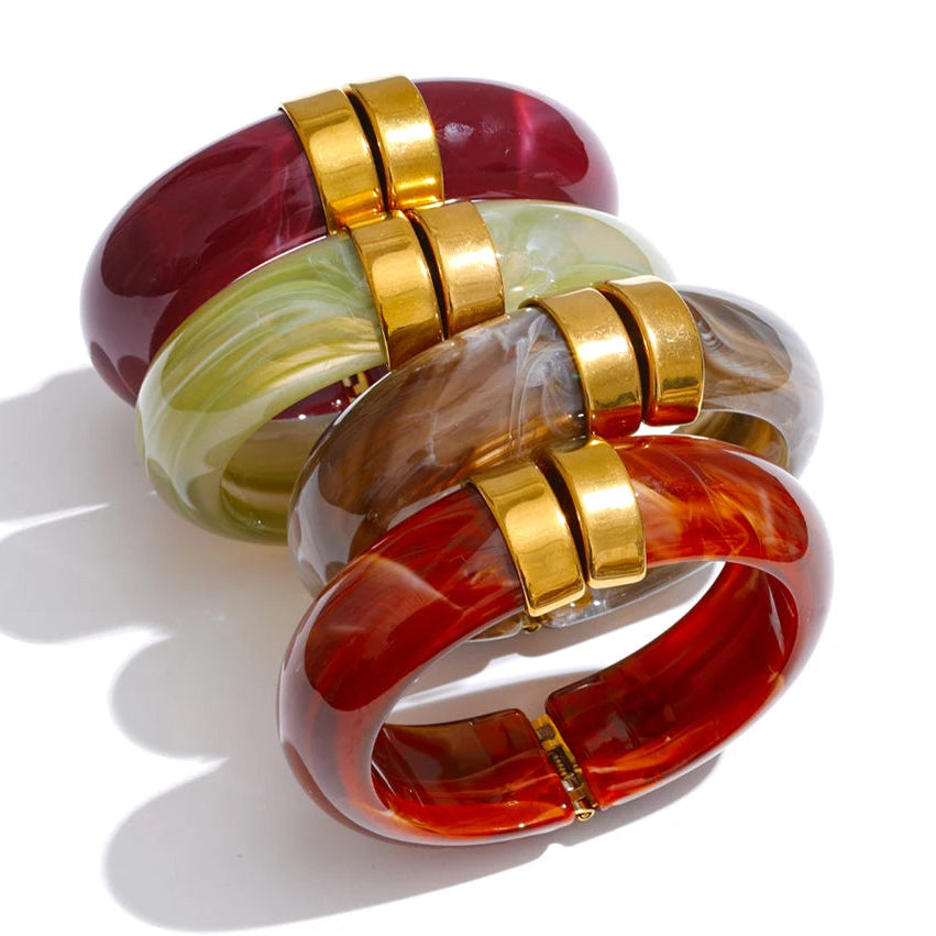 Colourful resin bracelets with gold accents on a white background