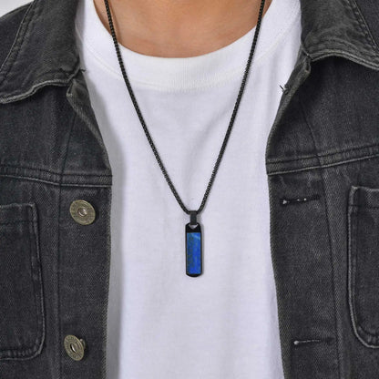 Person wearing a black necklace with a blue pendant on a plain background