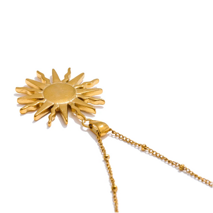 Gold sun-shaped pendant on a chain against a white background