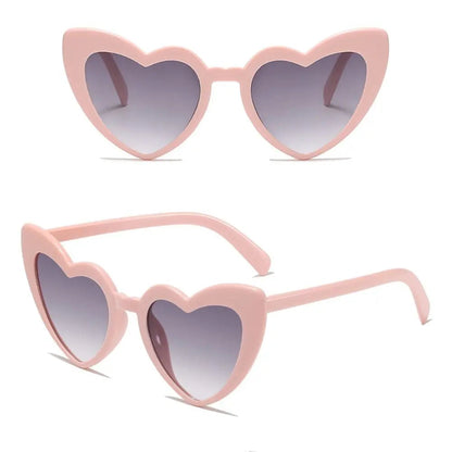 Heart-shaped sunglasses with pink frame and gradient lenses on a white background.