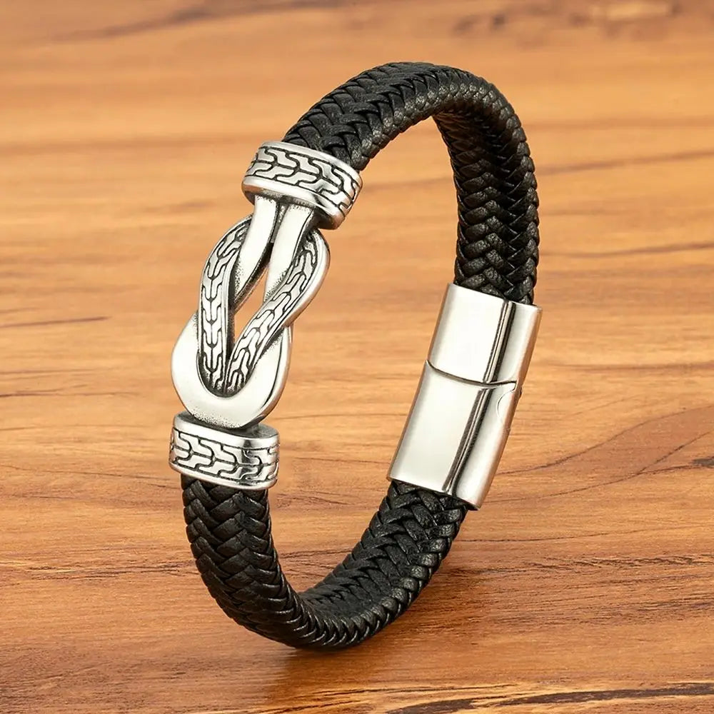 Black braided leather bracelet with silver clasp on a wooden surface
