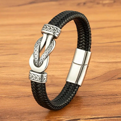 Black braided leather bracelet with silver clasp on a wooden surface