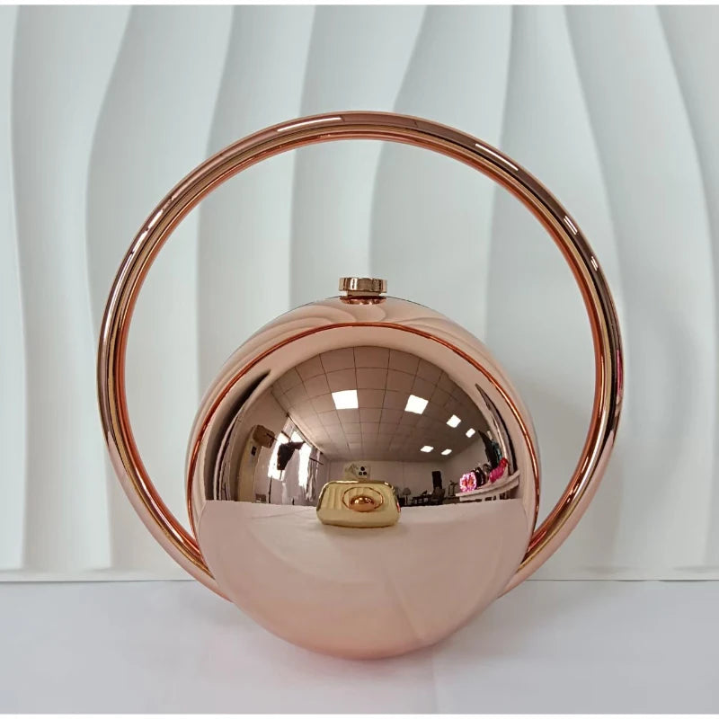 Rose gold circular handbag on a white background