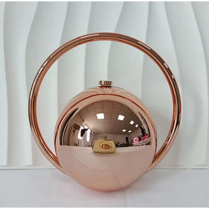 Rose gold circular handbag on a white background