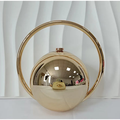 Gold spherical handbag with circular handle on a white background