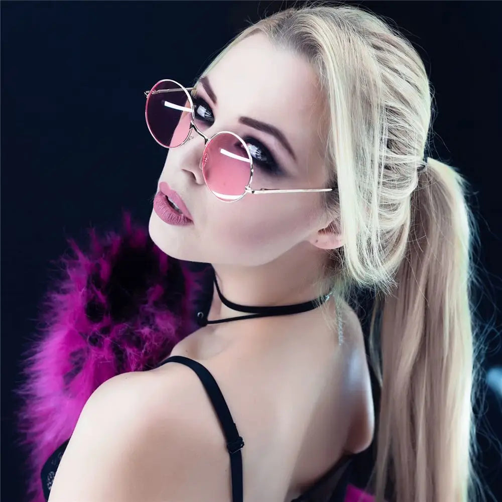 A woman wearing pink sunglasses on a black background.