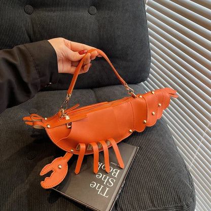 Person holding an orange lobster-shaped handbag with a book underneath.