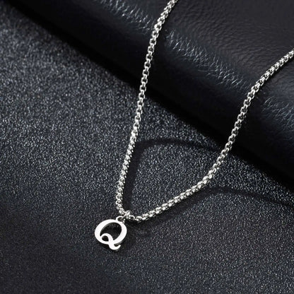 Silver necklace with a 'Q' pendant on a black textured surface