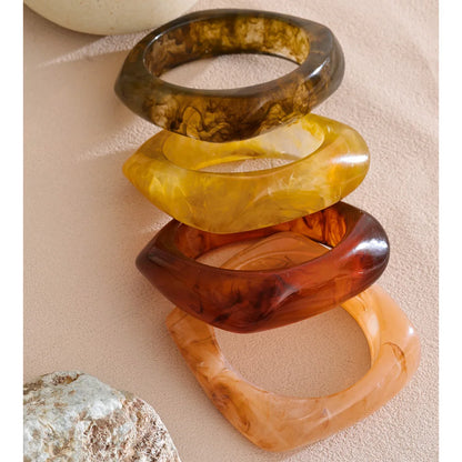 Stack of tortoiseshell bangles on a beige surface