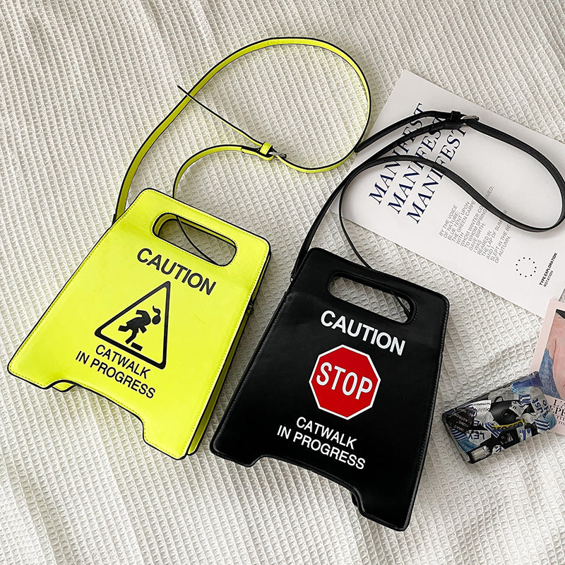 Two caution-style design bags, one yellow and one black, on a textured surface.