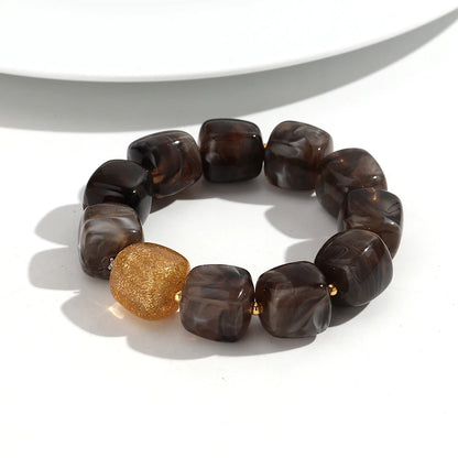 Bracelet with brown beads and a gold accent on a white background