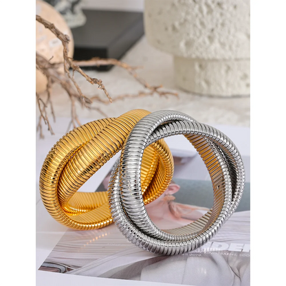 Gold and silver spiral bracelets on a magazine with a blurred background