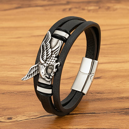 Black leather bracelet with silver eagle emblem on a wooden surface