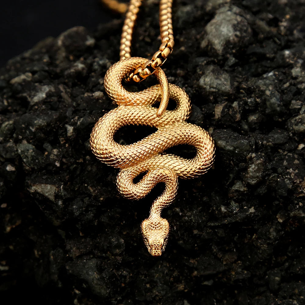 Gold snake pendant necklace on a dark textured surface