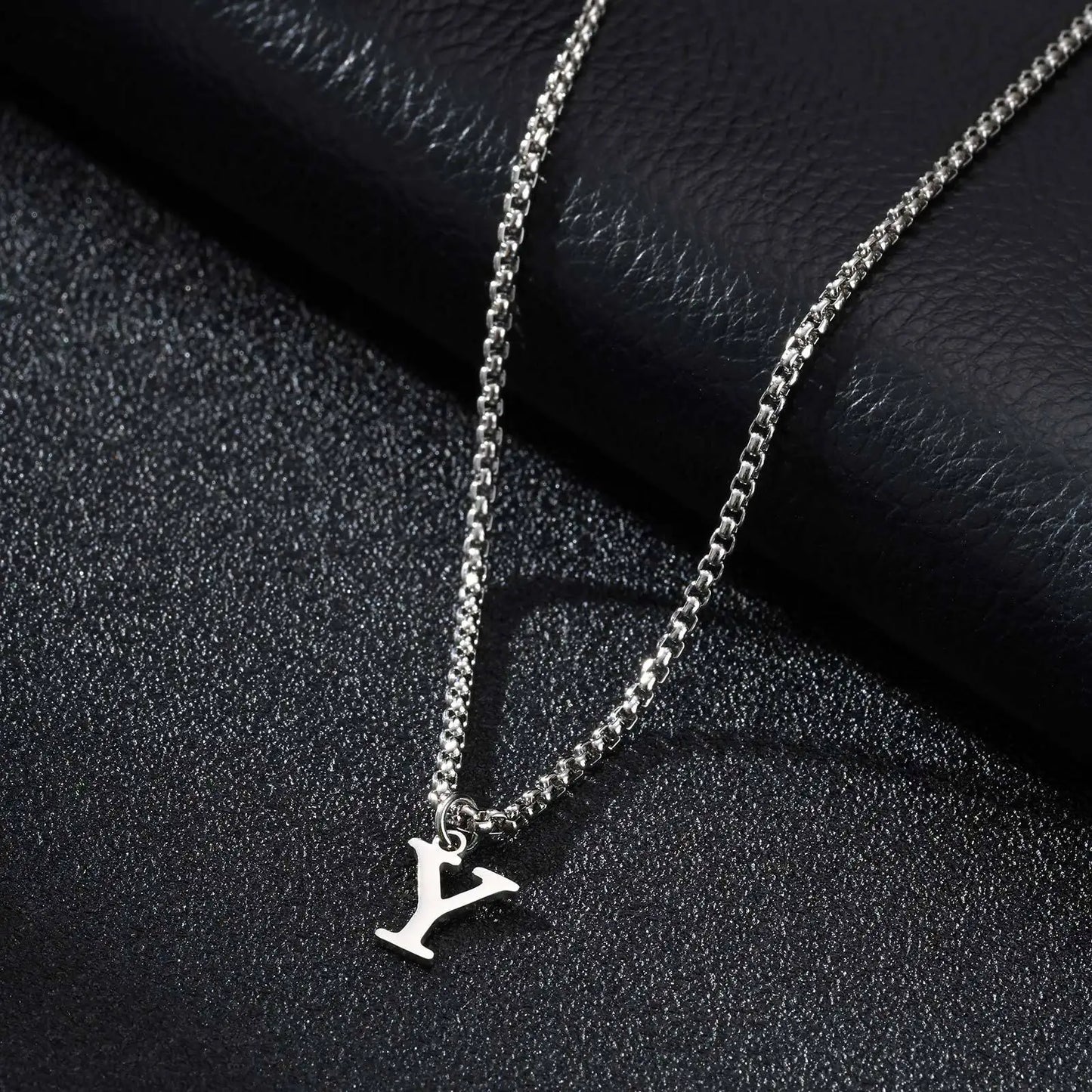 Silver necklace with a 'Y' pendant on a black textured surface