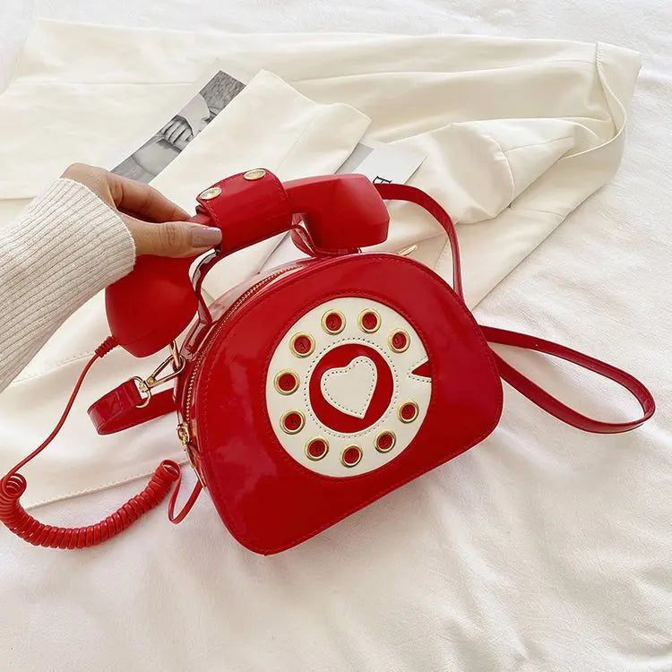 Red phone-shaped bag with a heart design on a white surface