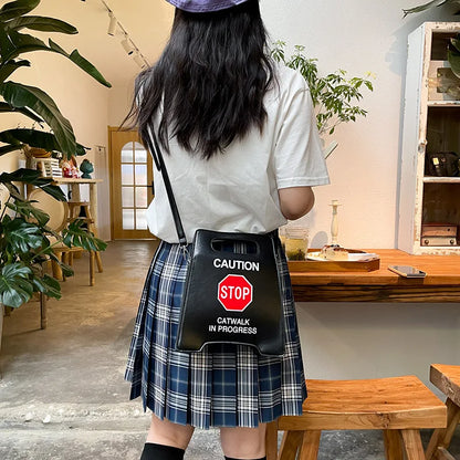 Person wearing a white shirt and plaid skirt with a black bag featuring a stop sign design.