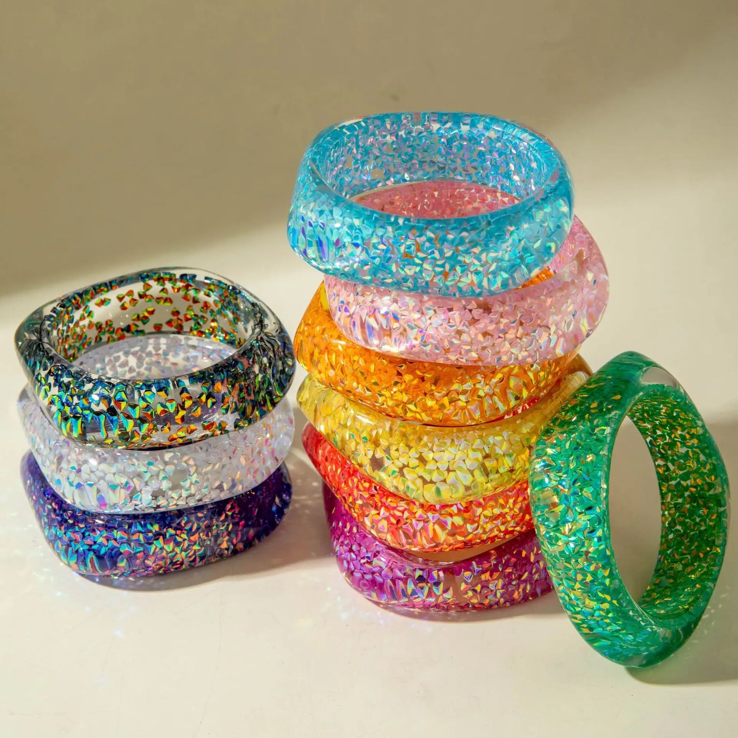 Stack of colourful glittery bangles on a light background