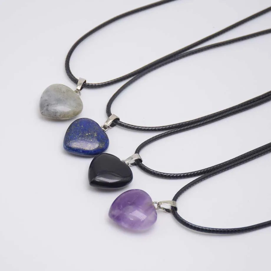 Four heart-shaped stone pendants on black cords against a white background