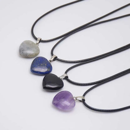 Four heart-shaped stone pendants on black cords against a white background