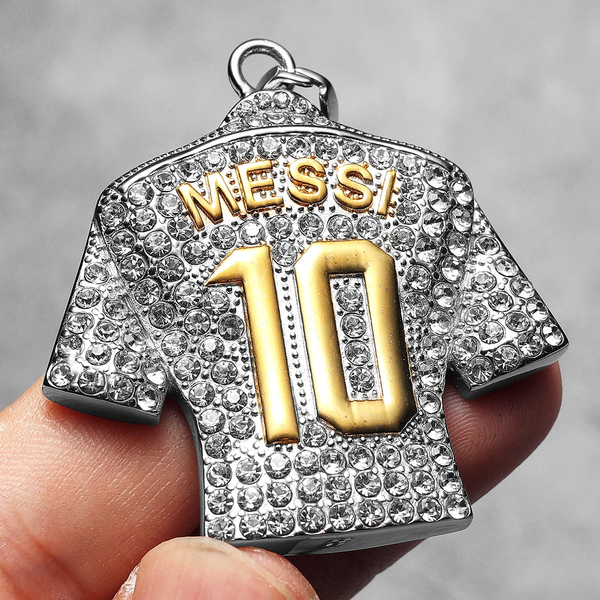 Pendant designed like a sports jersey with 'MESSI' and number '10', held by a hand against a neutral background.
