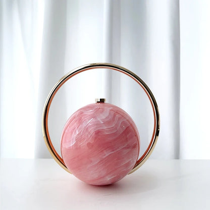 Pink marbleized handbag with gold circular handle on a white background