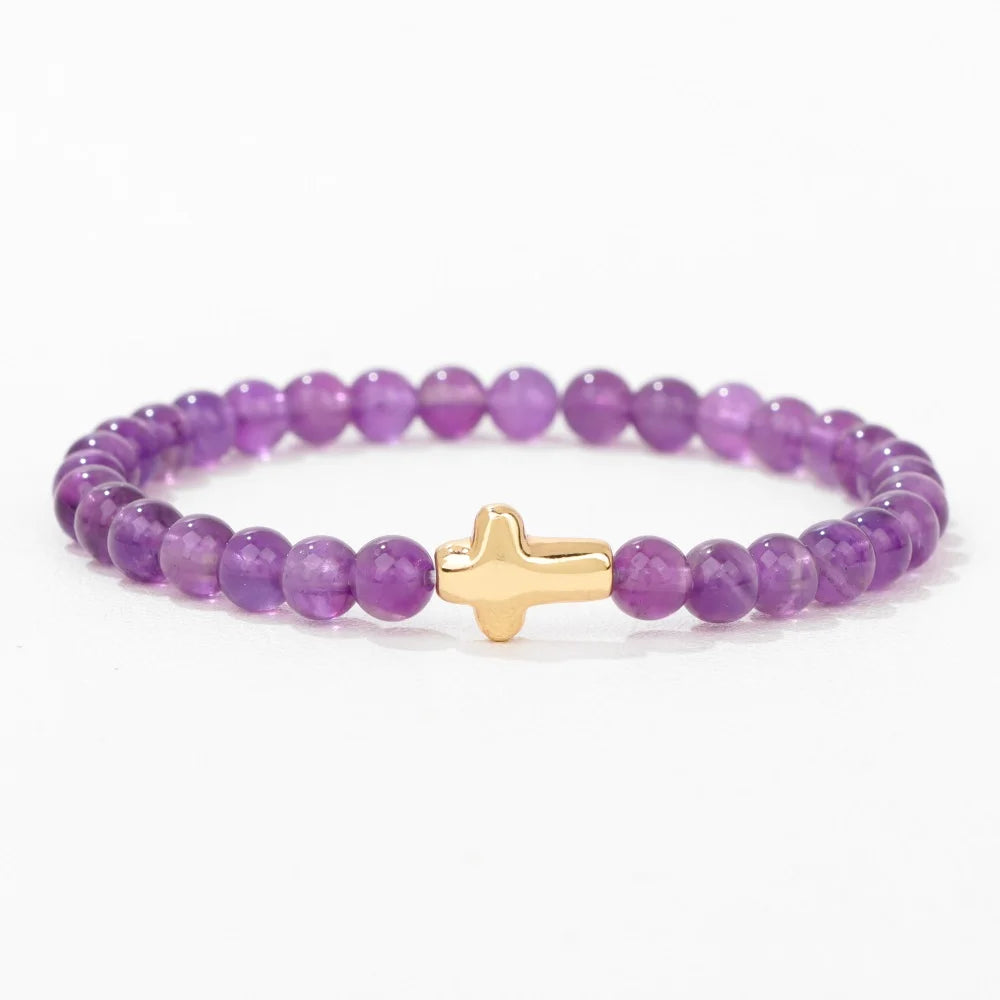 Purple beaded bracelet with a gold cross charm on a white background