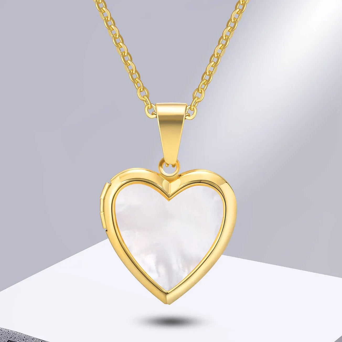 Gold heart-shaped pendant with a white center on a gray background