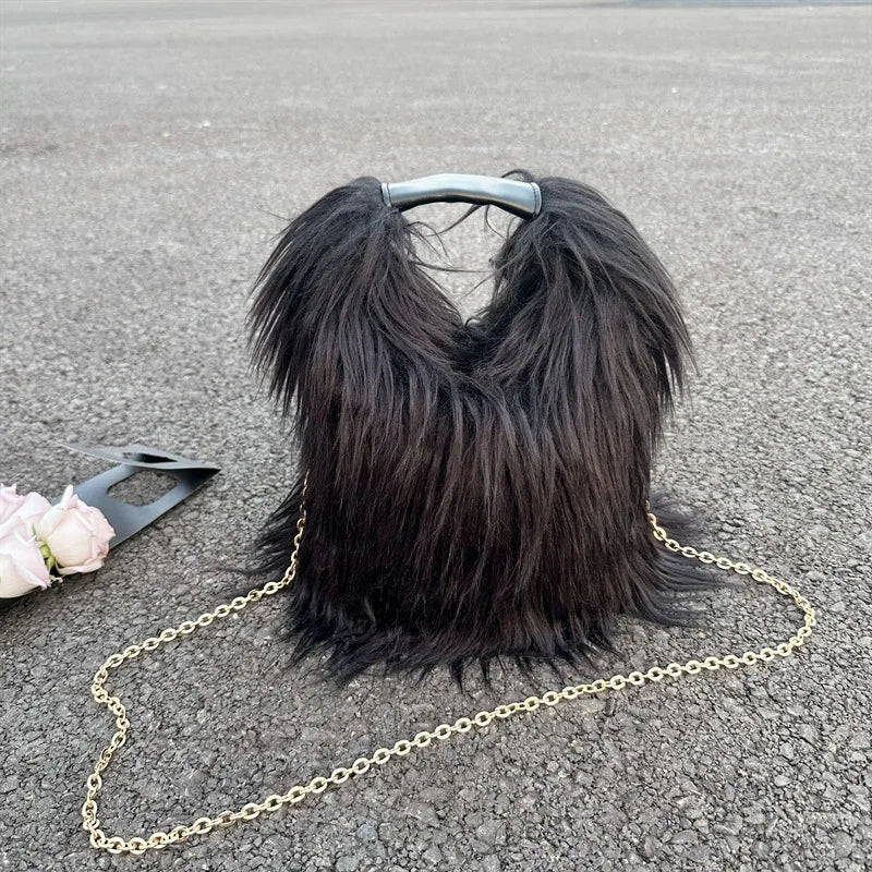 Black furry handbag with a gold chain on a gray surface