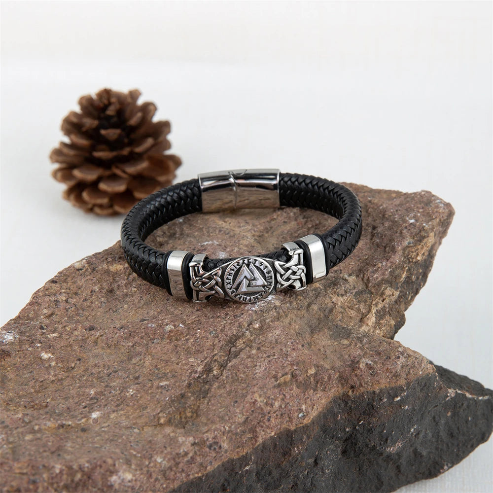 Black leather bracelet with silver metal clasp on a stone surface