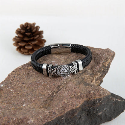 Black leather bracelet with silver metal clasp on a stone surface