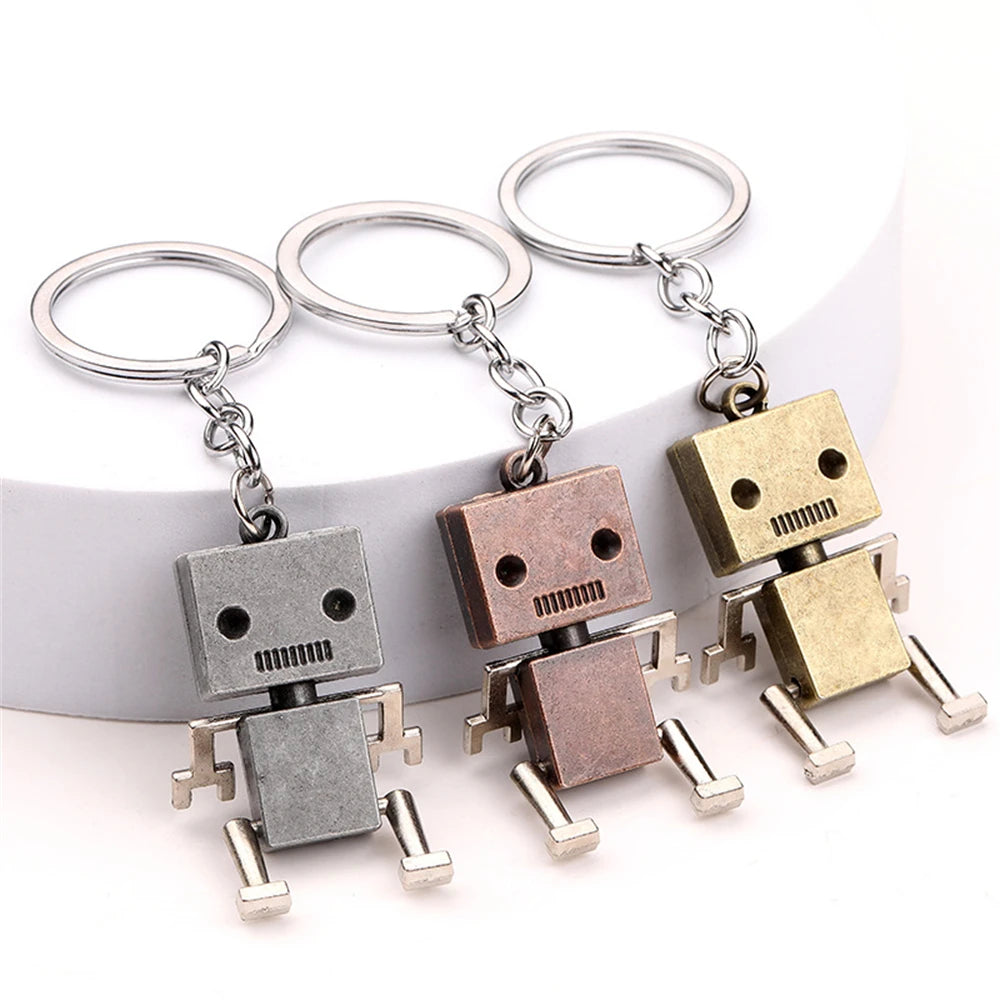 Three metal robot keyrings in silver, bronze and gold colour on white background