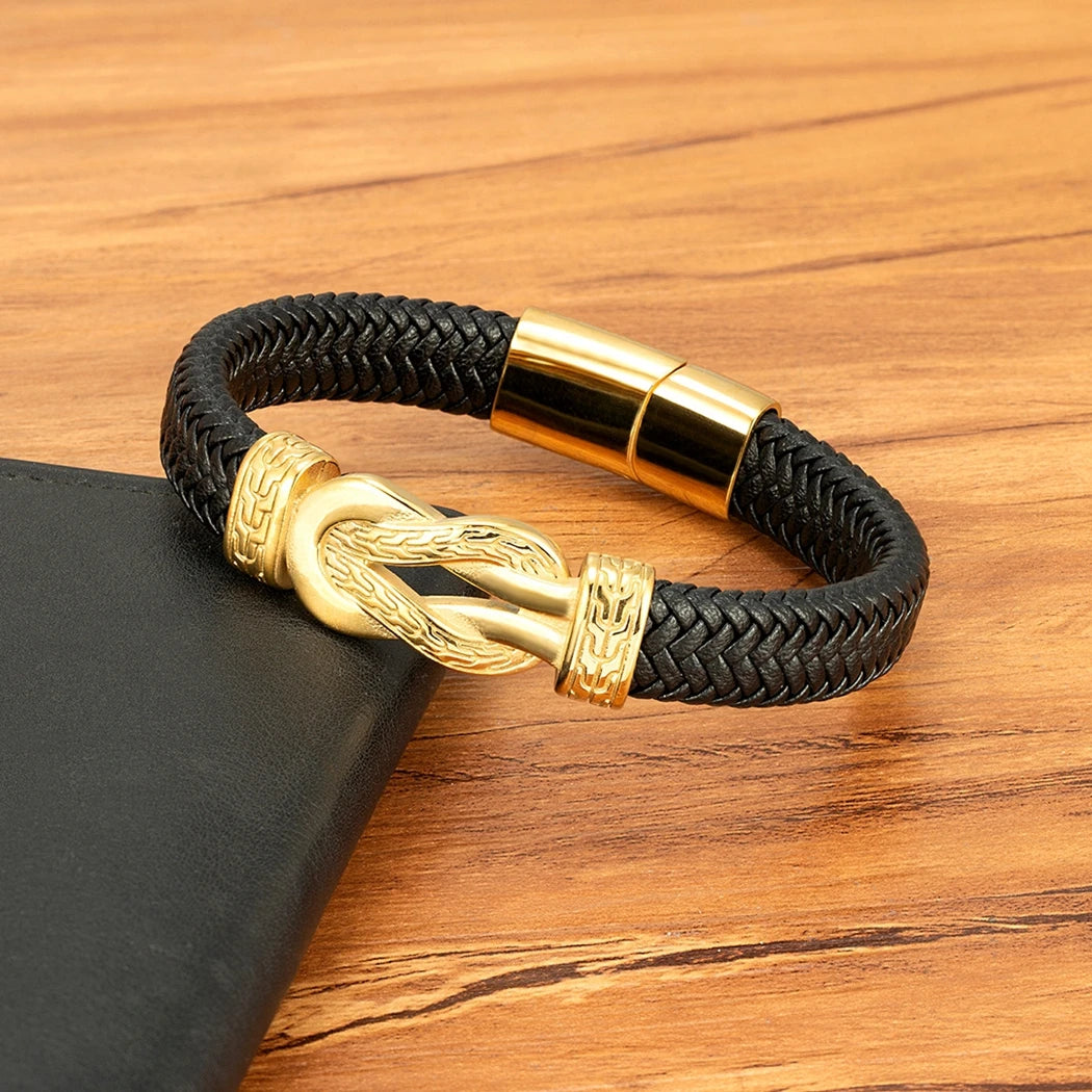 Black braided bracelet with gold clasp on a wooden surface