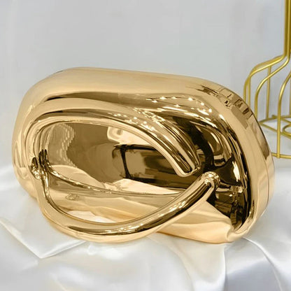 Gold metallic clutch on a white fabric background