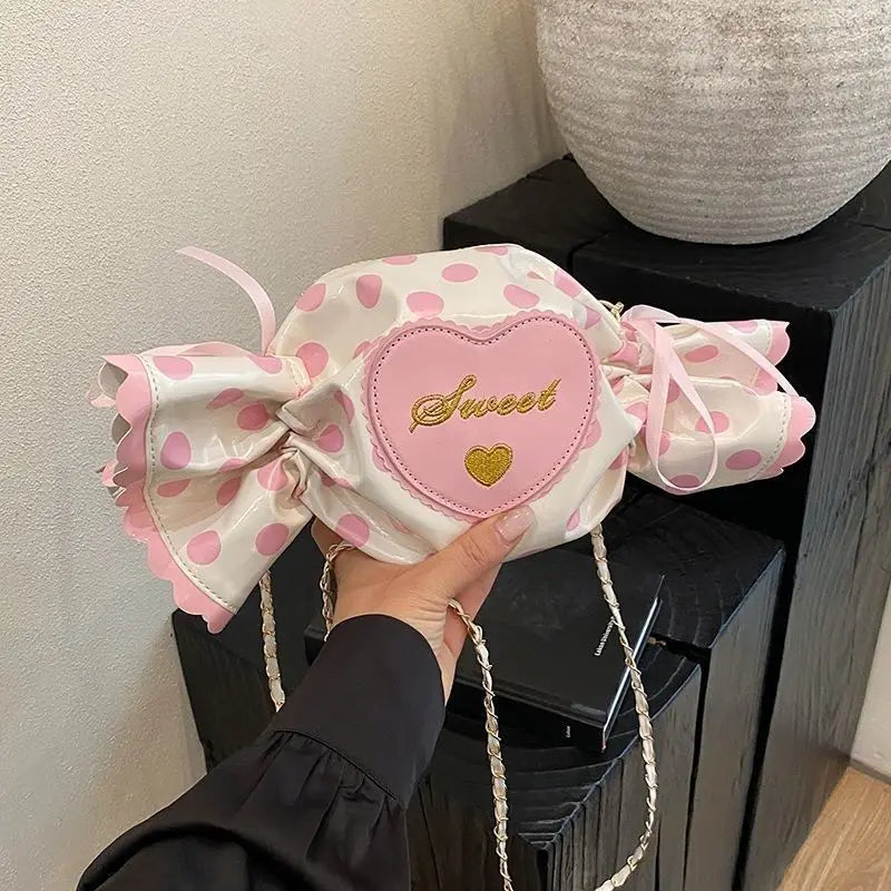 Pink polka dot bag with a heart-shaped patch and 'Sweet' text, held by a hand.