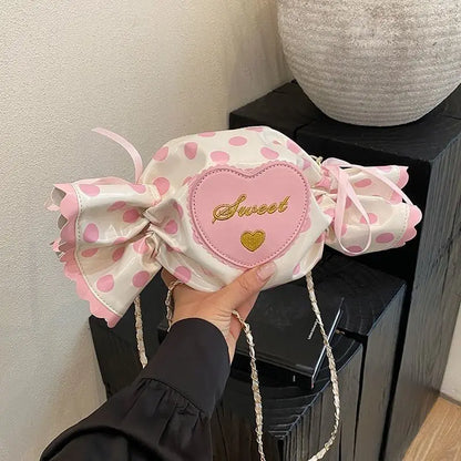 Pink polka dot bag with a heart-shaped patch and 'Sweet' text, held by a hand.