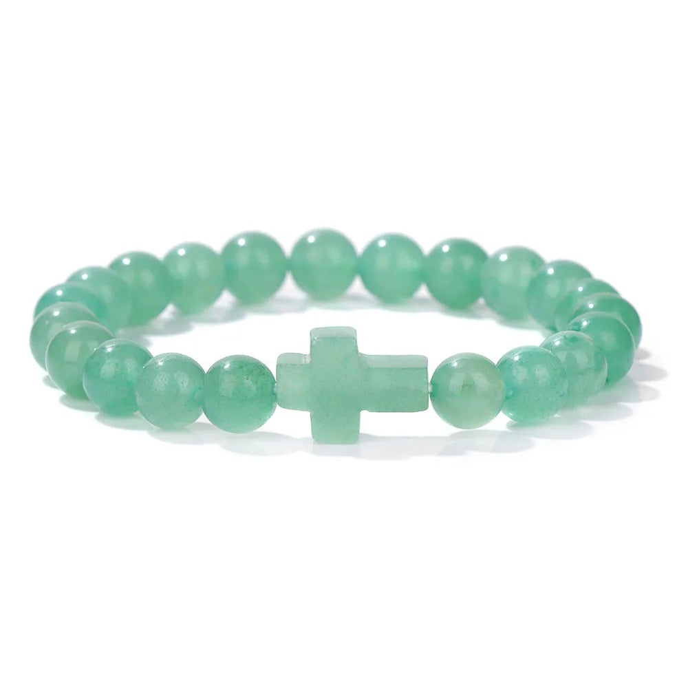 Green beaded bracelet with a cross charm on a white background