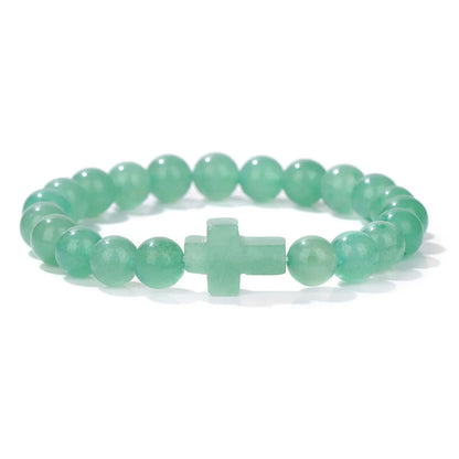 Green beaded bracelet with a cross charm on a white background