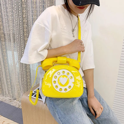 Person holding a yellow phone-shaped bag with a heart design.