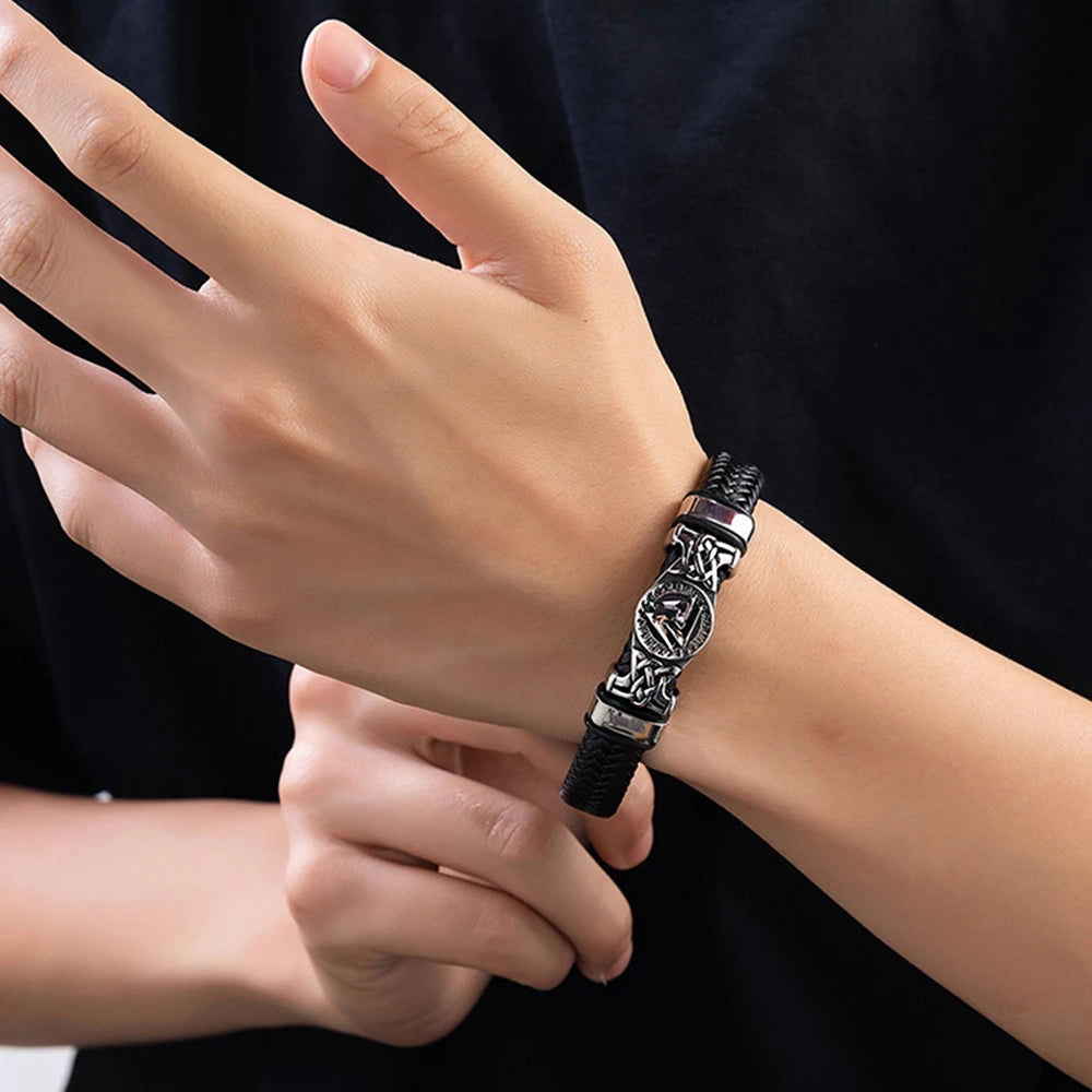 Close-up of a hand wearing a black and silver bracelet against a dark background