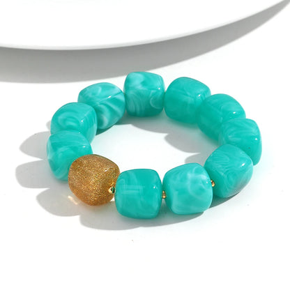 Turquoise beaded bracelet with a gold accent on a white background