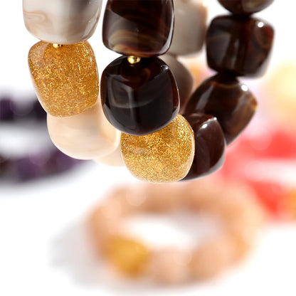 Close-up of a beaded bracelet with gold and brown beads on a blurred background