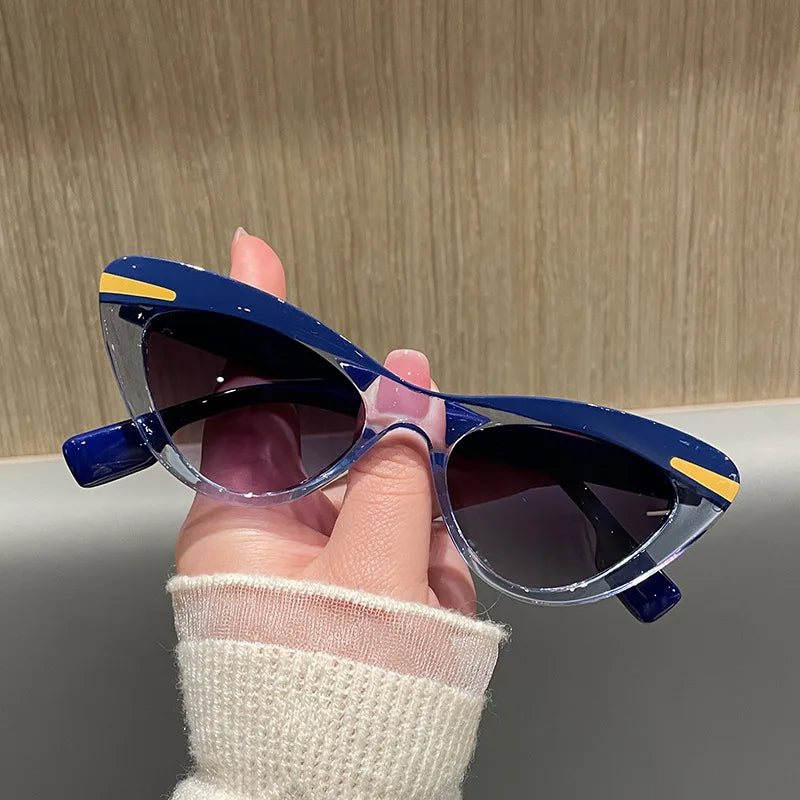 Hand holding a pair of blue sunglasses with yellow accents against a neutral background