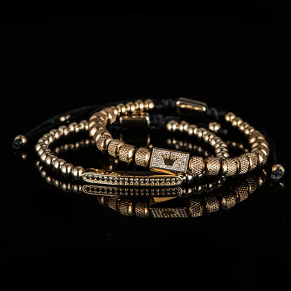 Gold beaded bracelets on a reflective black surface