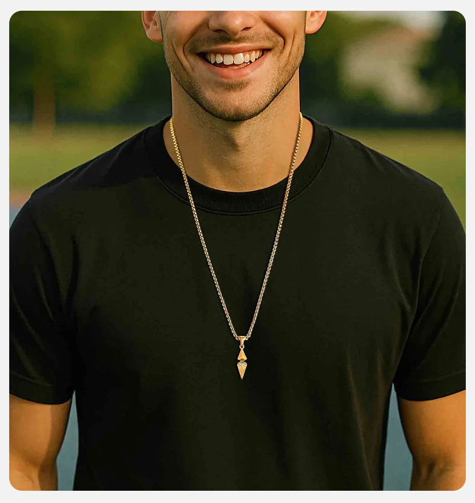Man wearing a black t-shirt and gold necklace with a pendant outdoors