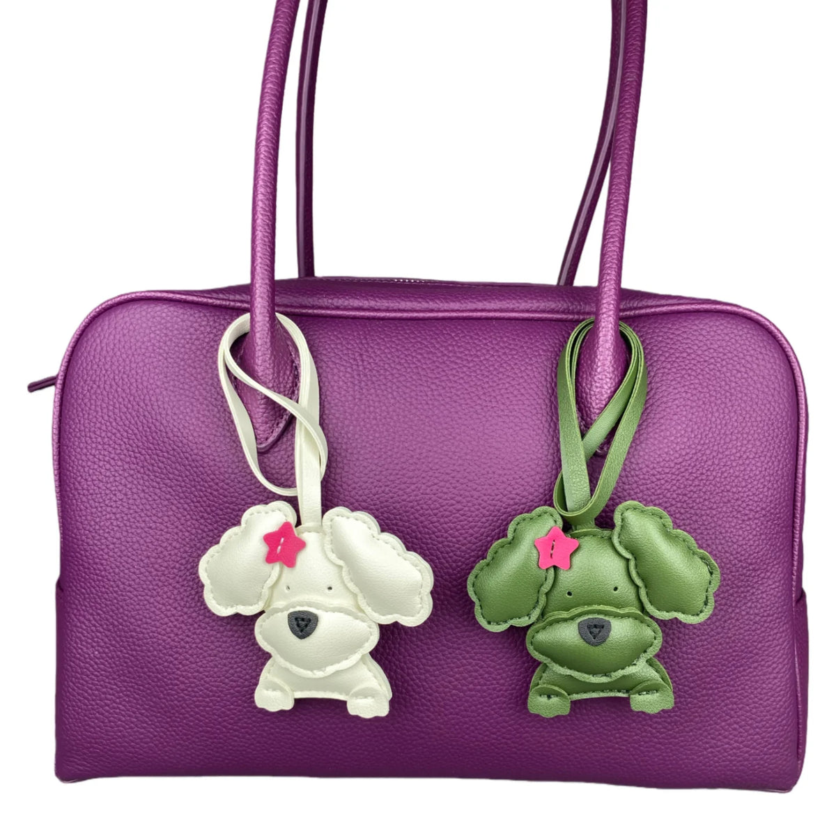 Purple handbag with two dog-shaped charms on a white background