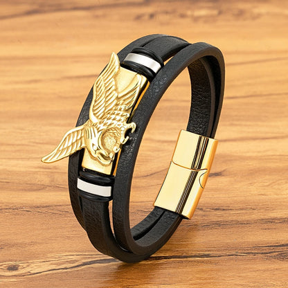 Black leather bracelet with gold eagle emblem on a wooden surface