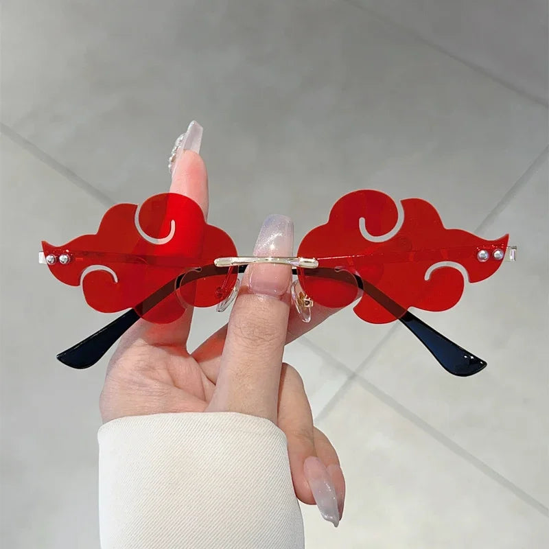 Sunglasses with red cloud design held by a hand against a light background
