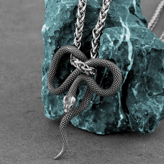 Silver snake necklace on a textured stone surface