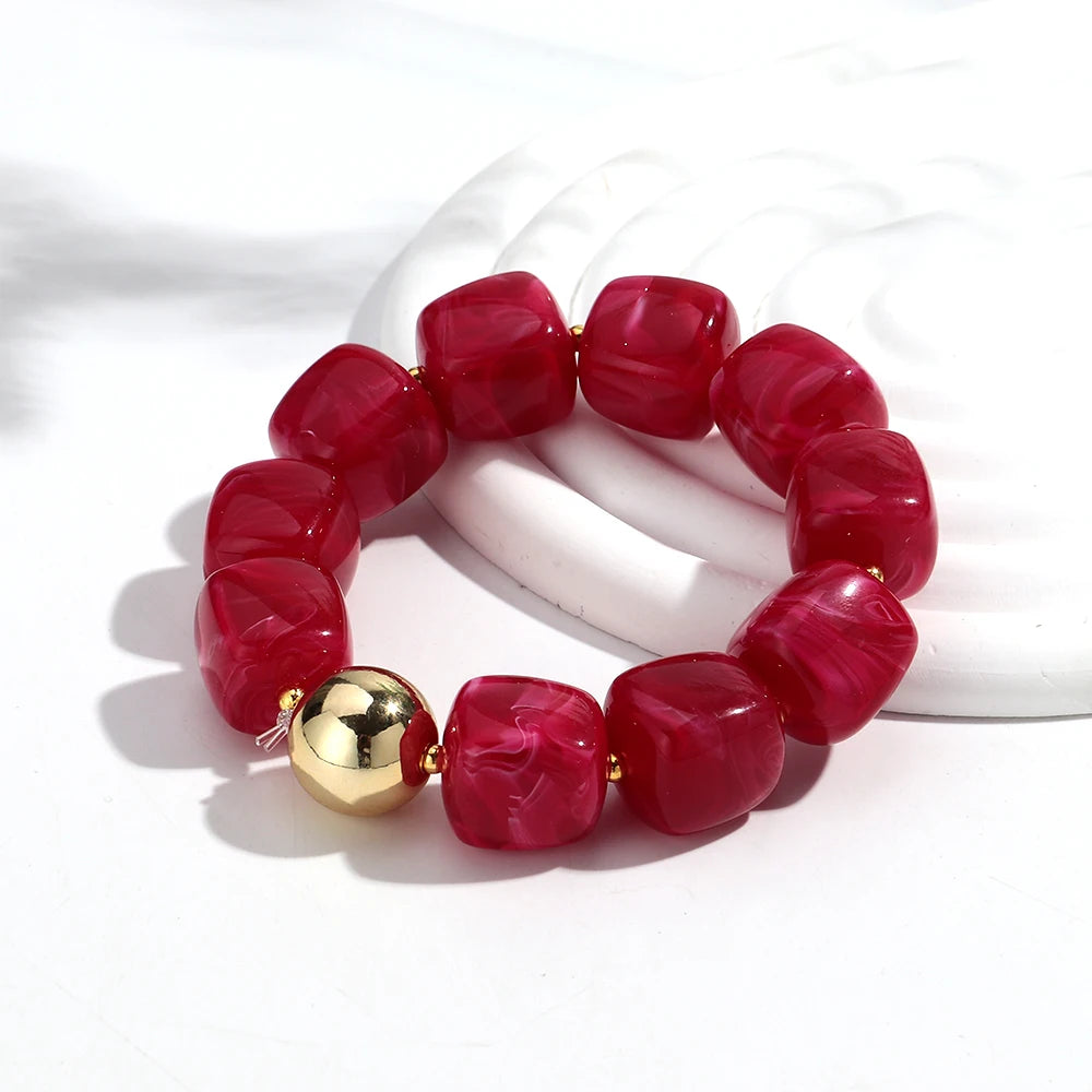Red beaded bracelet with a gold accent on a white background